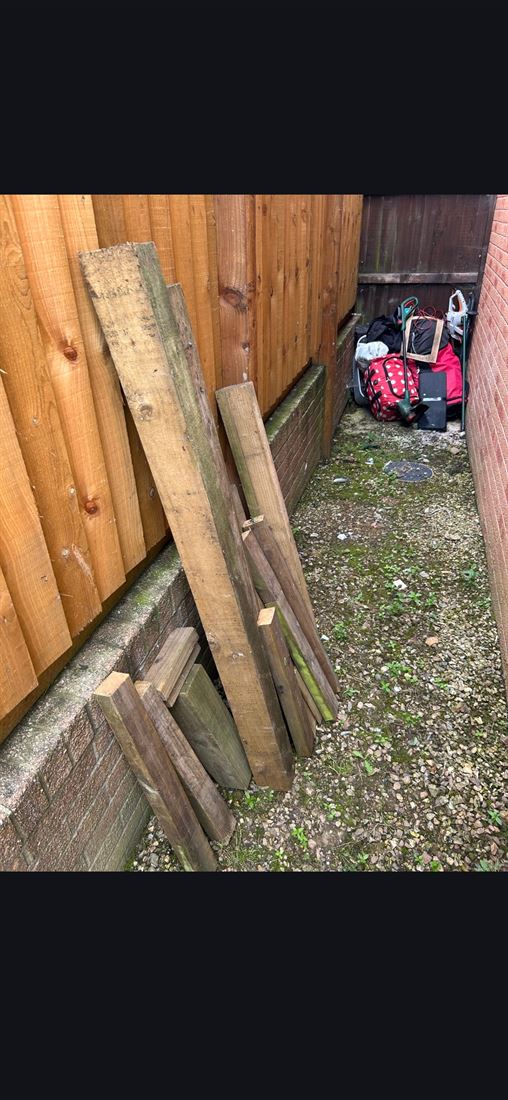 Old timber and fence panels stacked in a narrow side alley