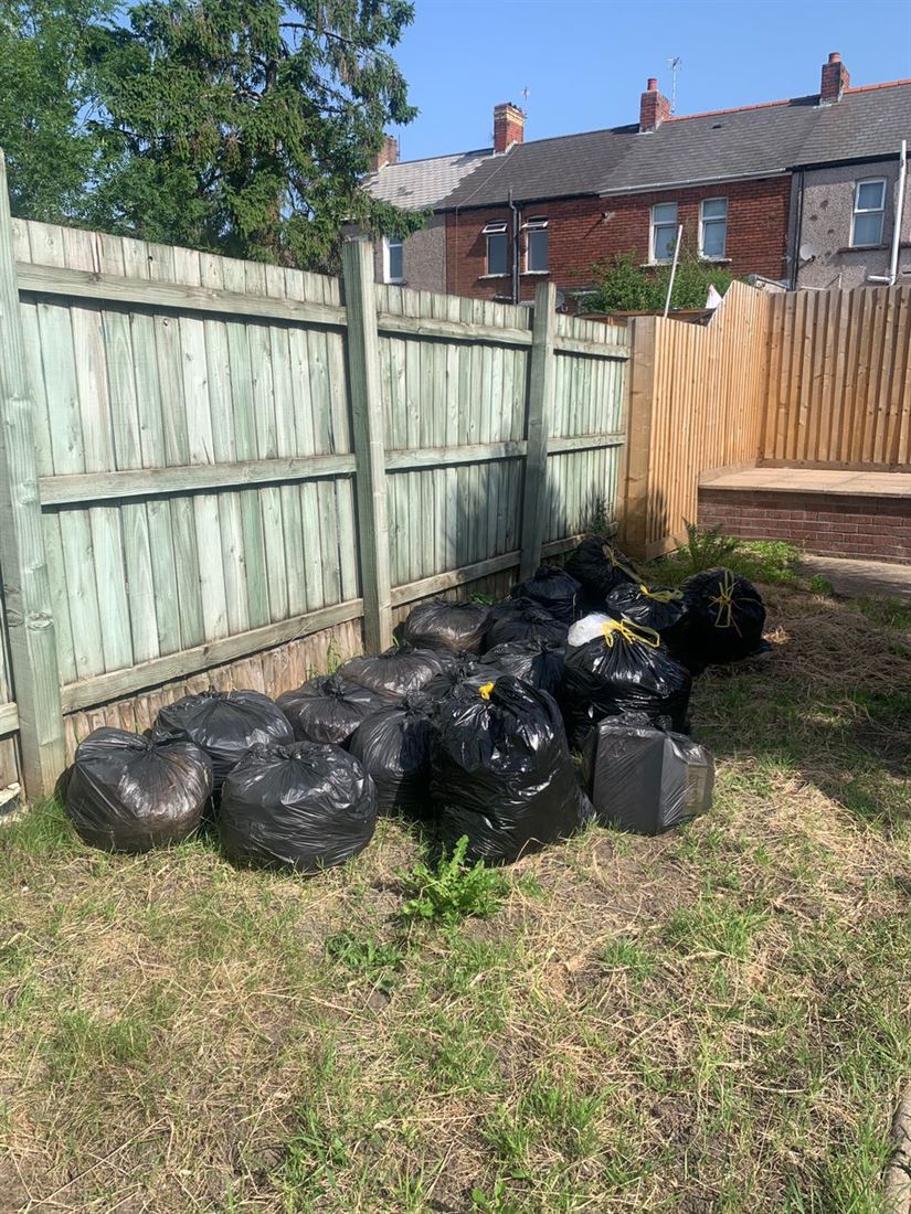 Around twenty full rubbish bags stacked in a terraced back garden
