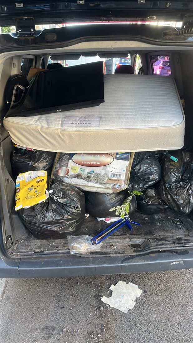 A van packed with a mattress and rubbish bags